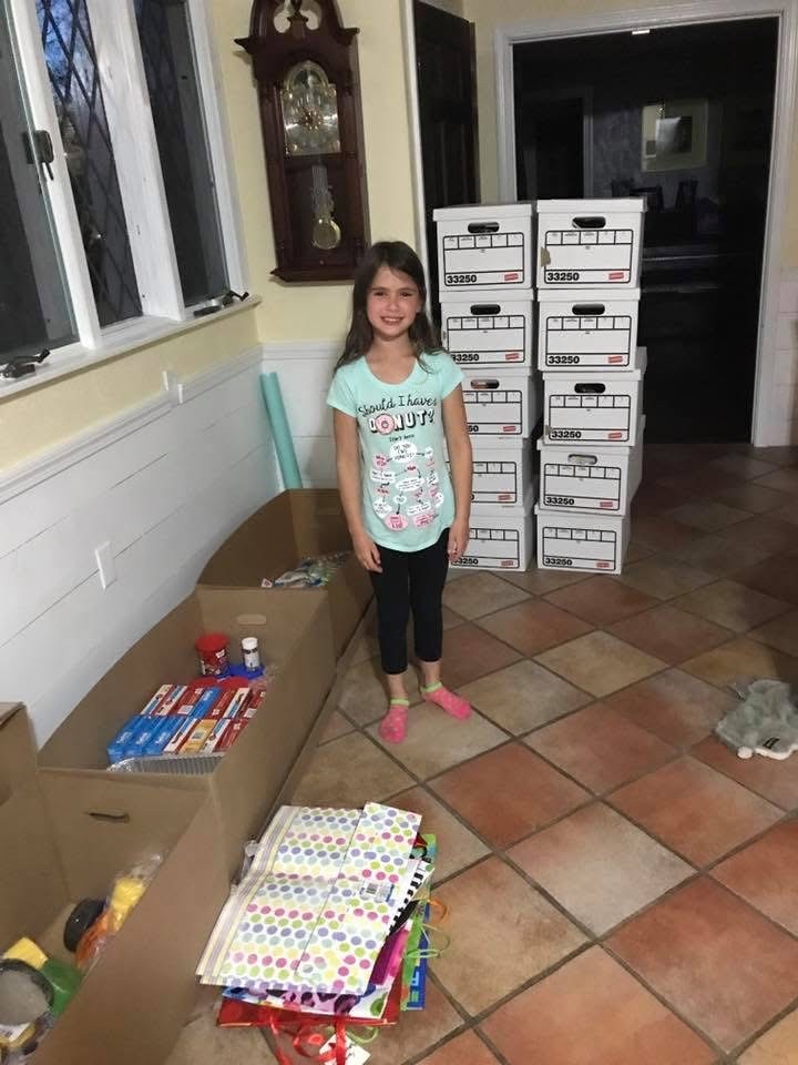 Young Ari beside boxes of supplies collected to help others.