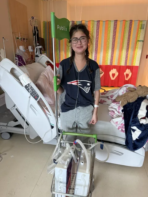 Ari standing beside her hospital bed.